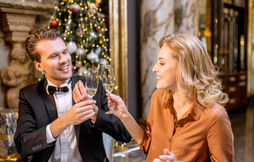 Blonde woman and man toasting in front of a Christmas tree in a restaurant