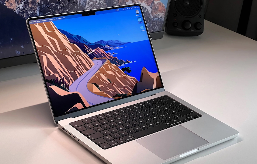 A silver Macbook pro 14 on a white table 