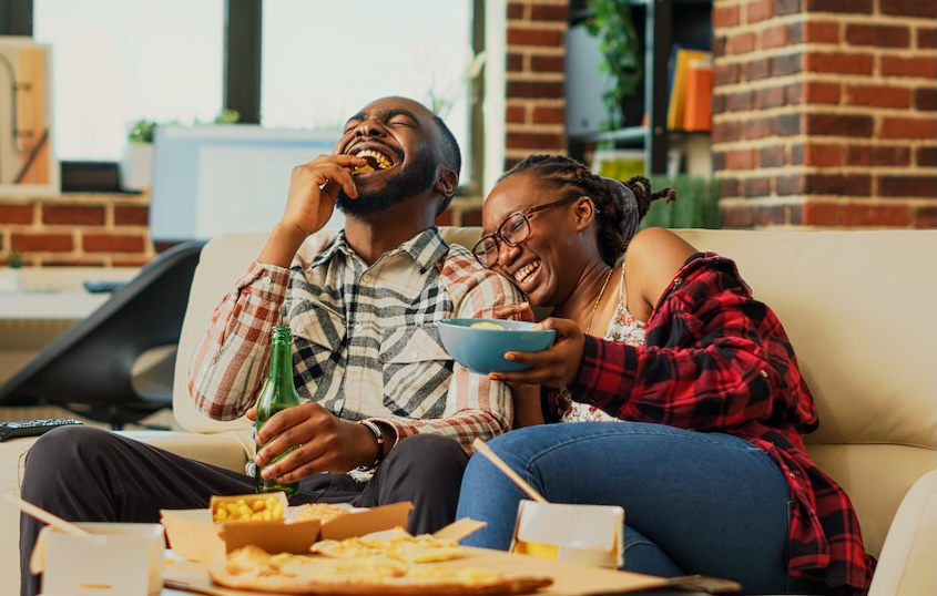 Black couple sitting on the couch while eating fast food